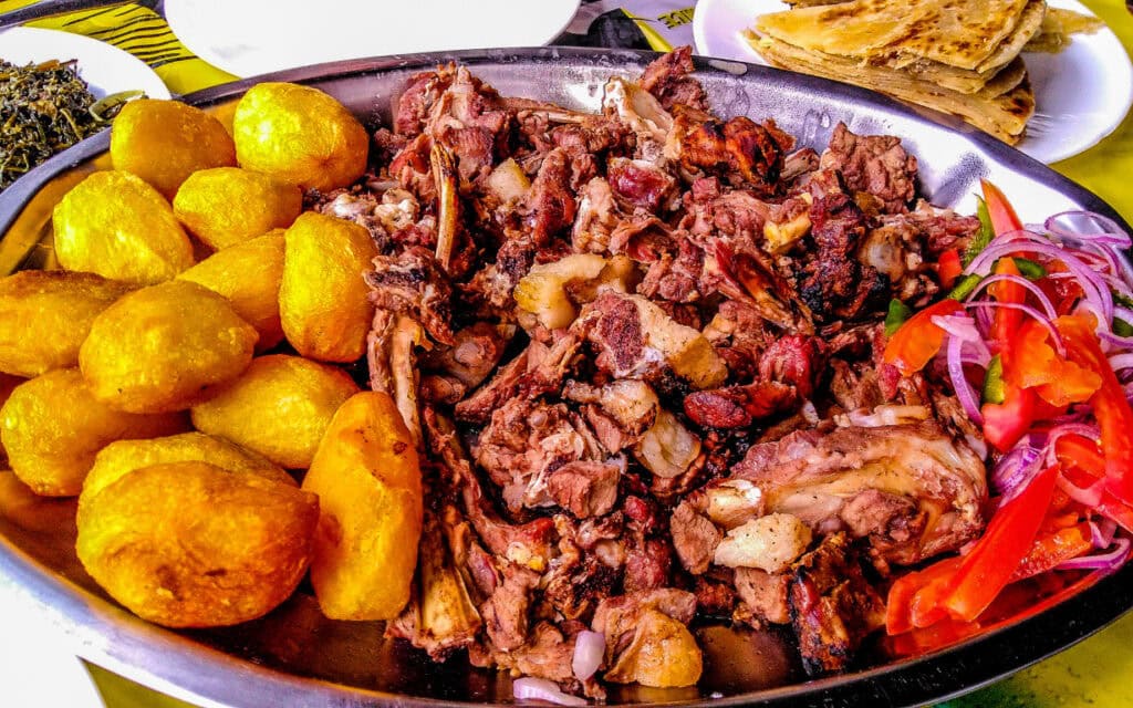 Sharing platter of a traditional Kenyan dish, Nyama choma and accompaniments of kachumbari salad | Photo: Jennifer Watson via Getty