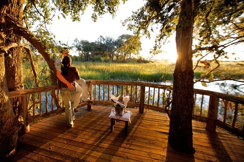 Couple on honeymoon enjoy the view from the deck at Gunn's Camp in Botswna Photo credit: Gunn's Camp