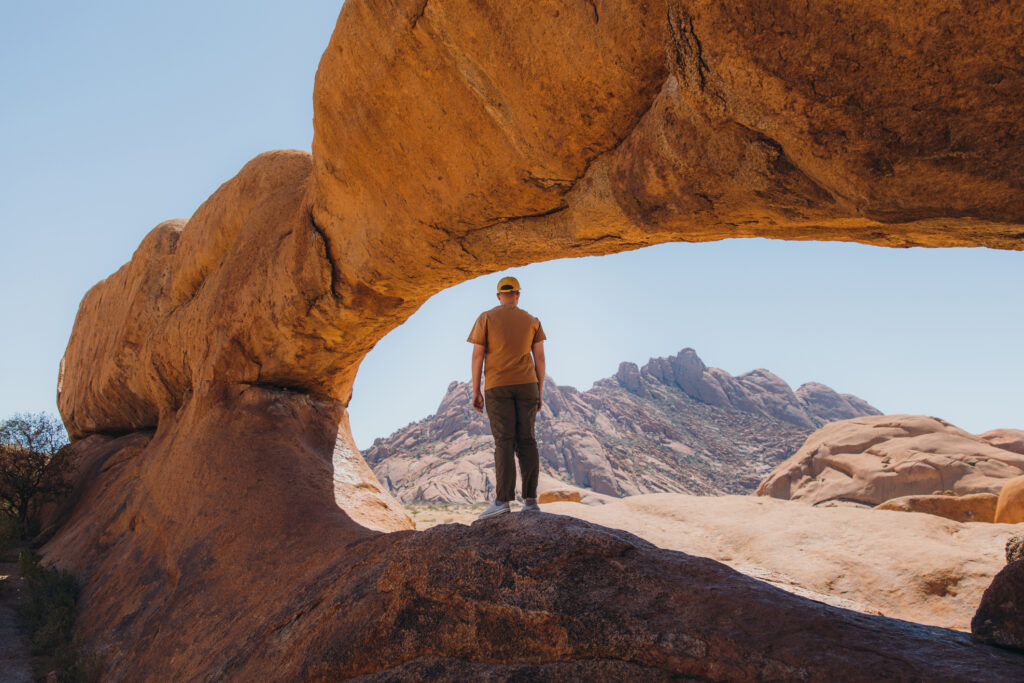 Male traveler exploring Spitzkoppe walking inside of the natural arch. Photo: Getty Images