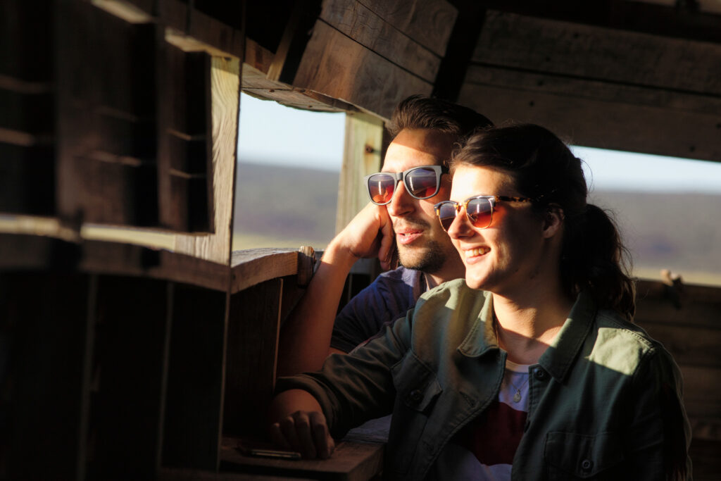 Young couple watching wildlife in observation hut during a visit to a national park in South Africa. Photo: Getty Images