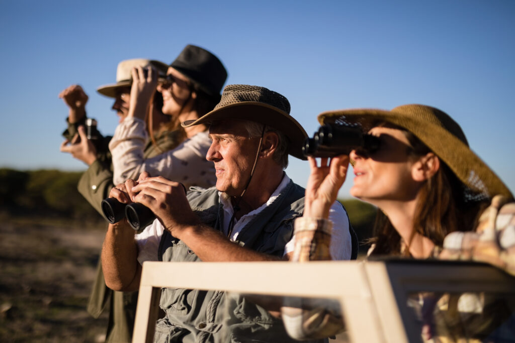 Group of friends looking through binoculars during safari vacation in South Africa. Photo: Getty Images