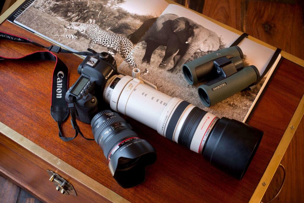 Camera and binoculars laying on a book of wildlife in Botswana. Photo: Great Plains